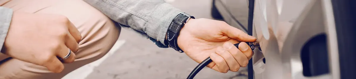 Nahaufnahme einer Hand, die einen Luftschlauch am Reifenventil eines Autos befestigt.