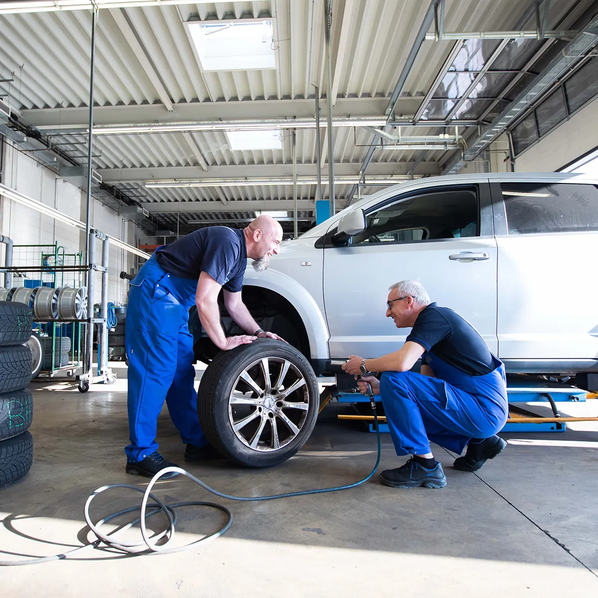 Zwei Mechaniker montieren ein Rad an einem Auto in der Werkstatt