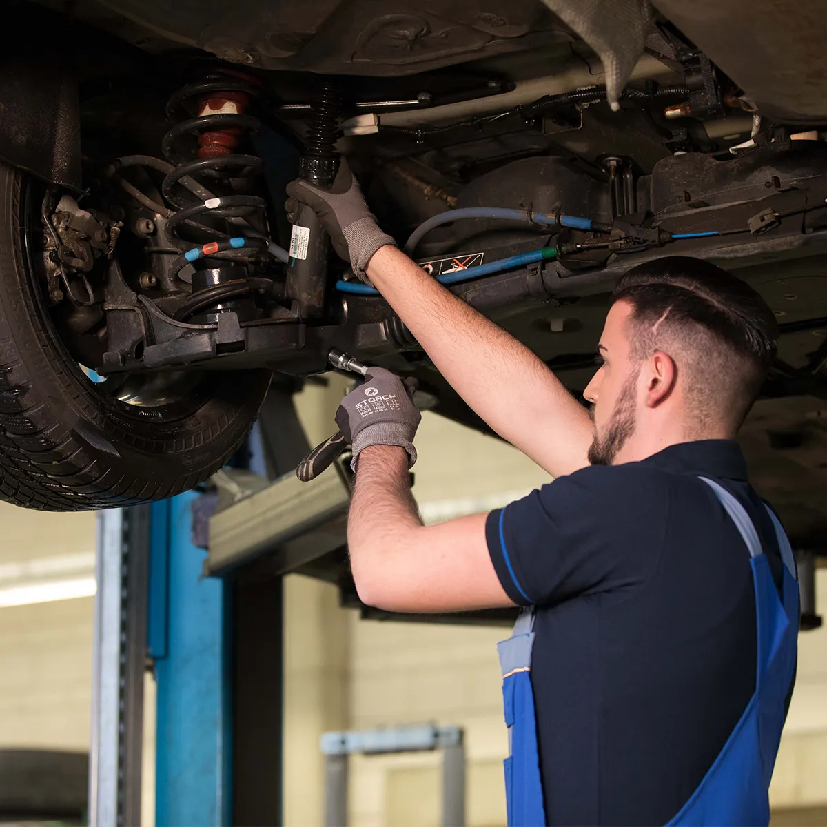 Stoßdämpfer am angehobenen Fahrzeug, Mechaniker mit Werkzeug