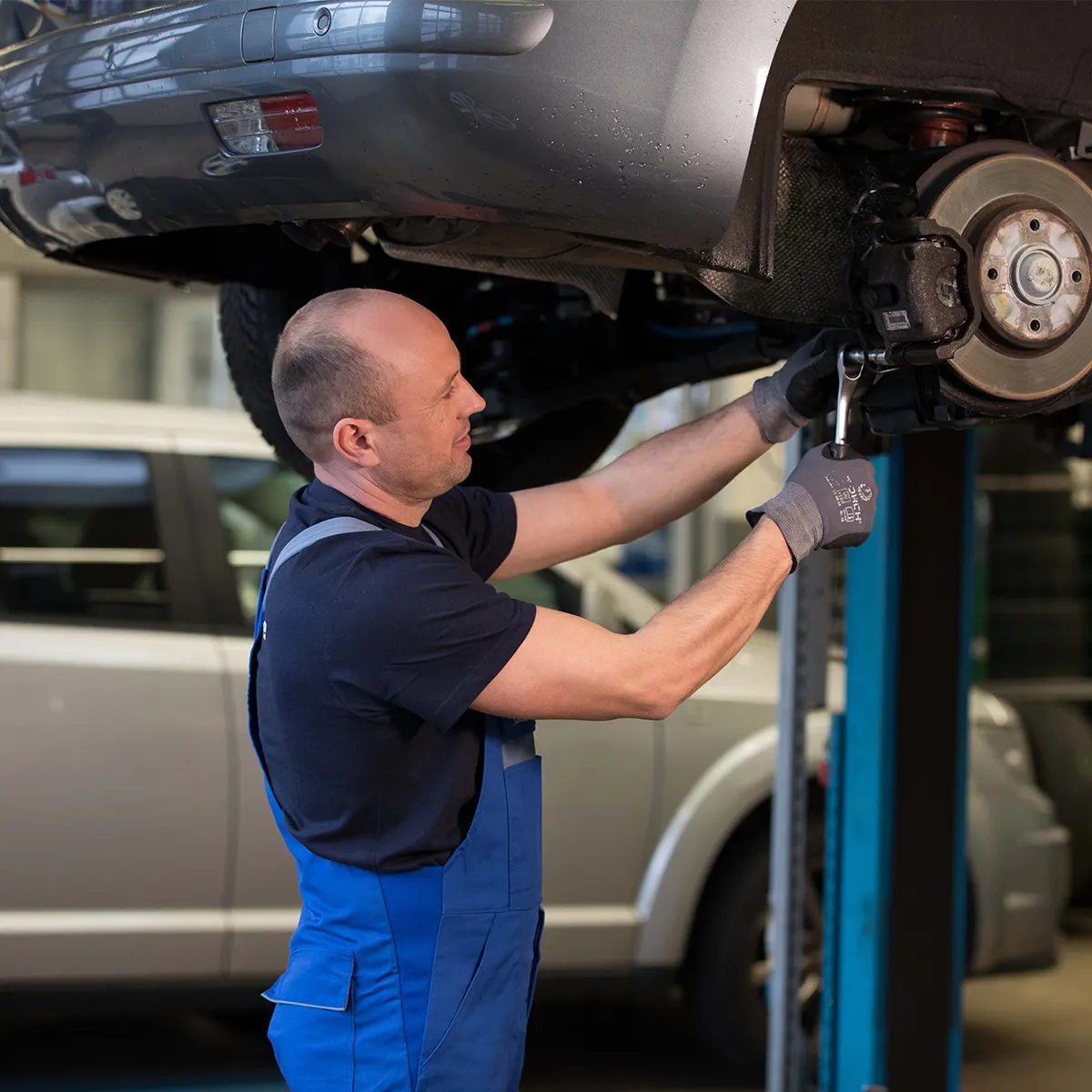 Mechaniker arbeitet an Bremsanlage am angehobenen Auto