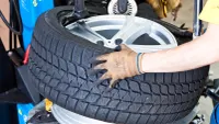 Werkstattmitarbeiter setzt Reifen auf Felge bei der Montage