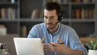 Mitarbeiter mit Headset und Notizstift bei einer Telefonberatung.