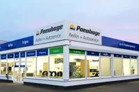 Nahaufnahme Pneuhage Reifen- und Autoservice-Filiale bei Dämmerung mit großen Schaufenstern und ausgestellten Reifen