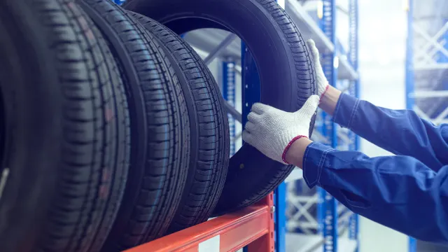 Mechaniker stellt Reifen in ein Regal zur fachgerechten Reifeneinlagerung