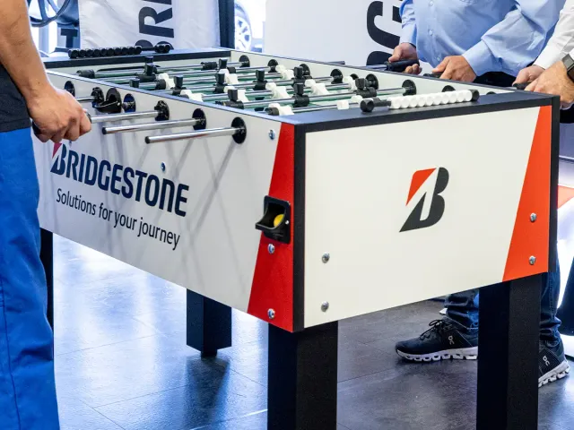 Nahaufnahme eines Tischkickers mit Händen und Füßen von Menschen, die eine Partie spielen