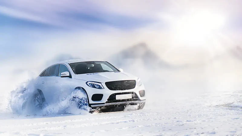 Bild Weißes Auto im Schnee mit starkem Schneestaub bei Winterfahrt